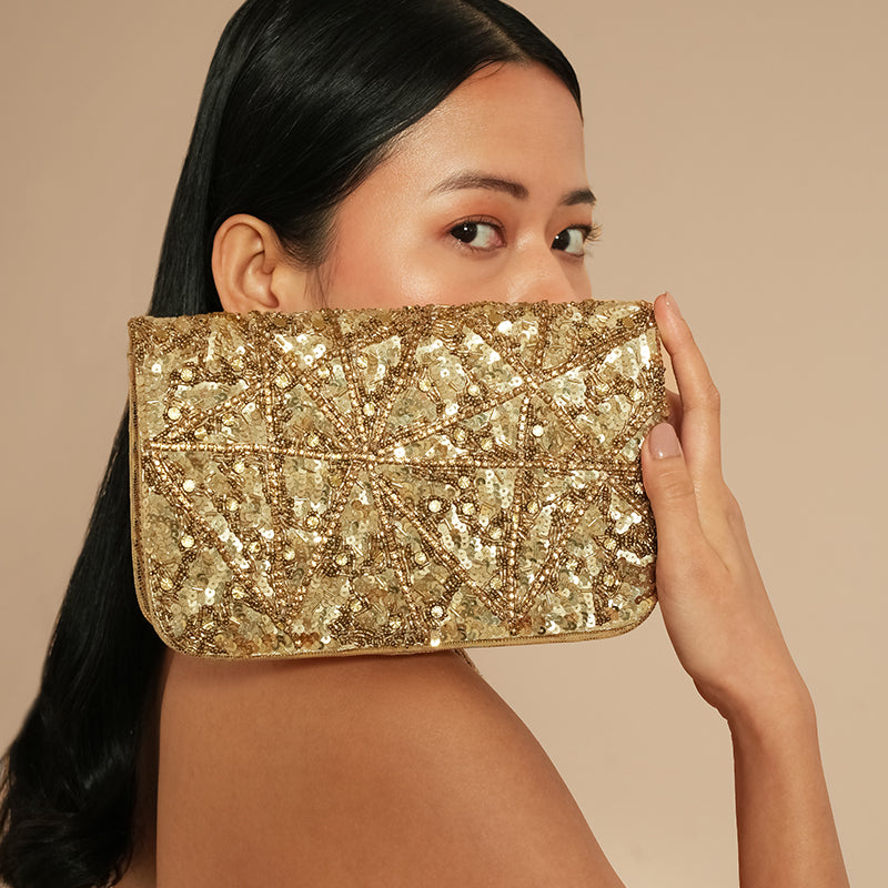 Model holding Terra Clutch in gold color