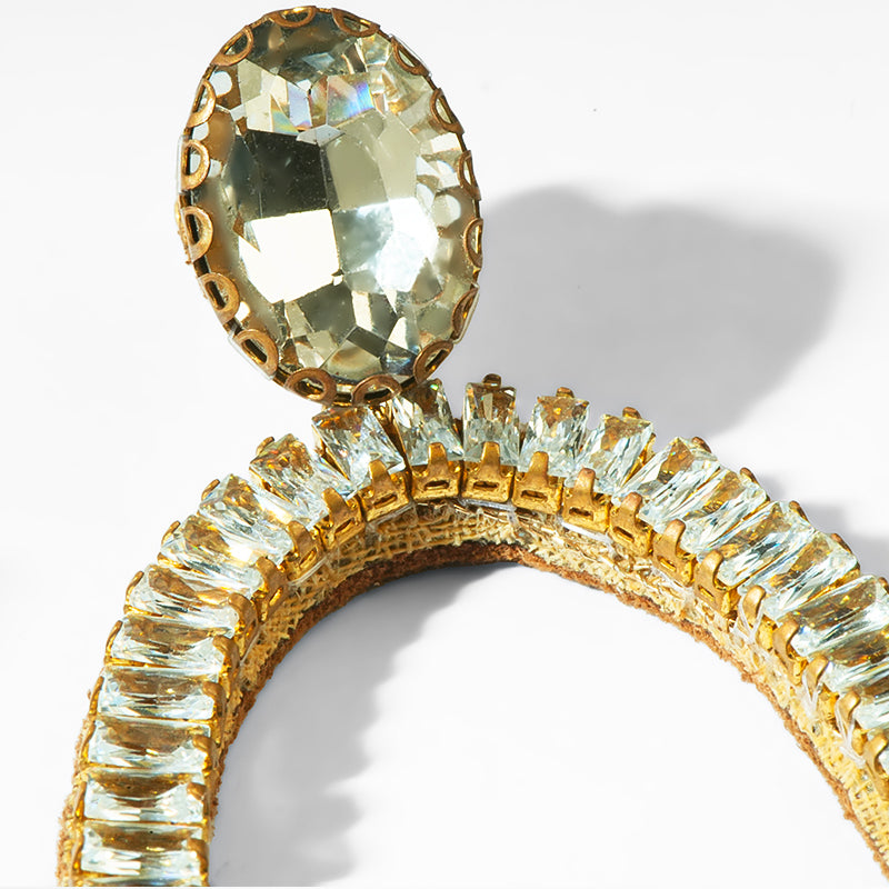 Gold earring with a large central gemstone and smaller ones along the band on a white background