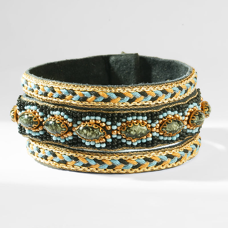 Multistrand bracelet with braided design and embedded stones on a white background