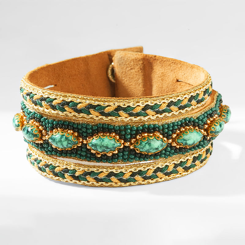 Green beaded bracelet with gold accents on a white background