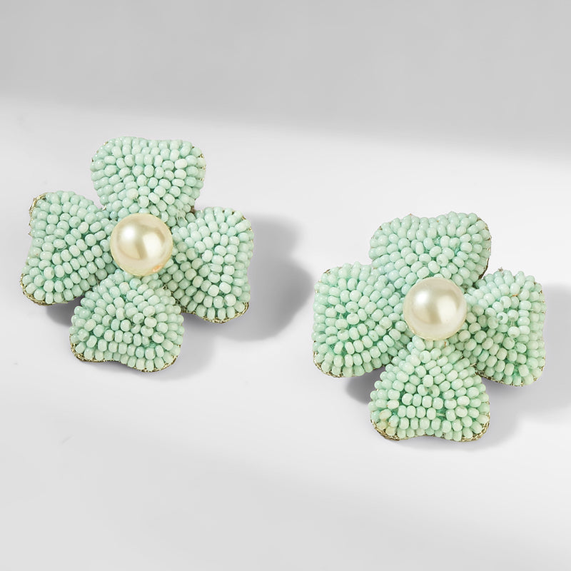 Pair of light blue flower-shaped earrings with pearl centers on a white background