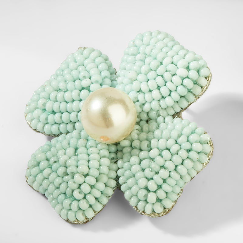 Light blue flower-shaped earrings with a pearl center on a white background
