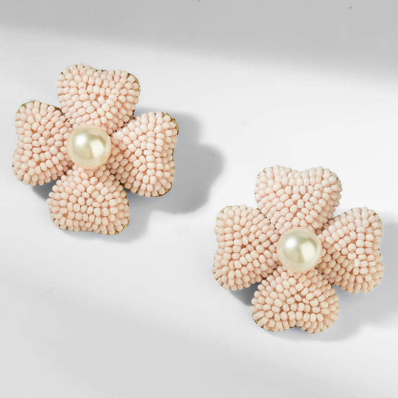 Pair of pink flower-shaped earrings with pearl centers on a light gray background