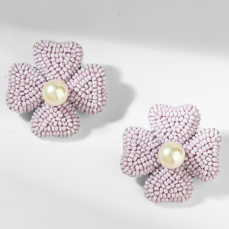 Pair of pink beaded flower earrings with pearl centers on a light gray background