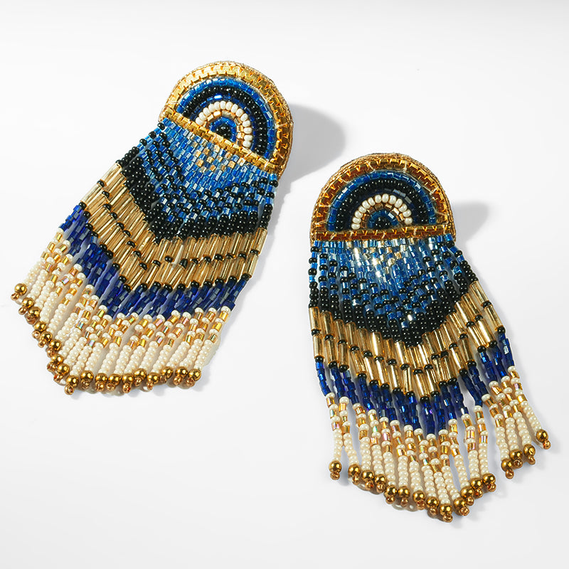 Beaded earrings with blue, gold, and white colors on a light gray background