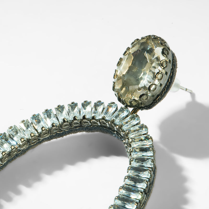 Silver earring with a large central gemstone and smaller ones along the band on a white background