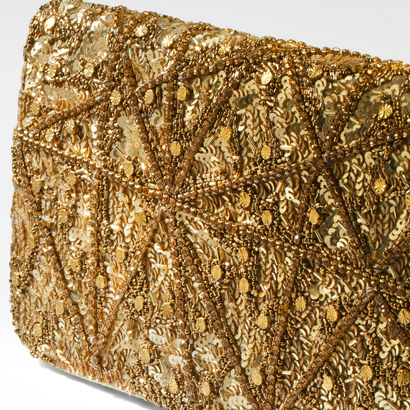Close up of gold sequin clutch bag with intricate pattern on a white background