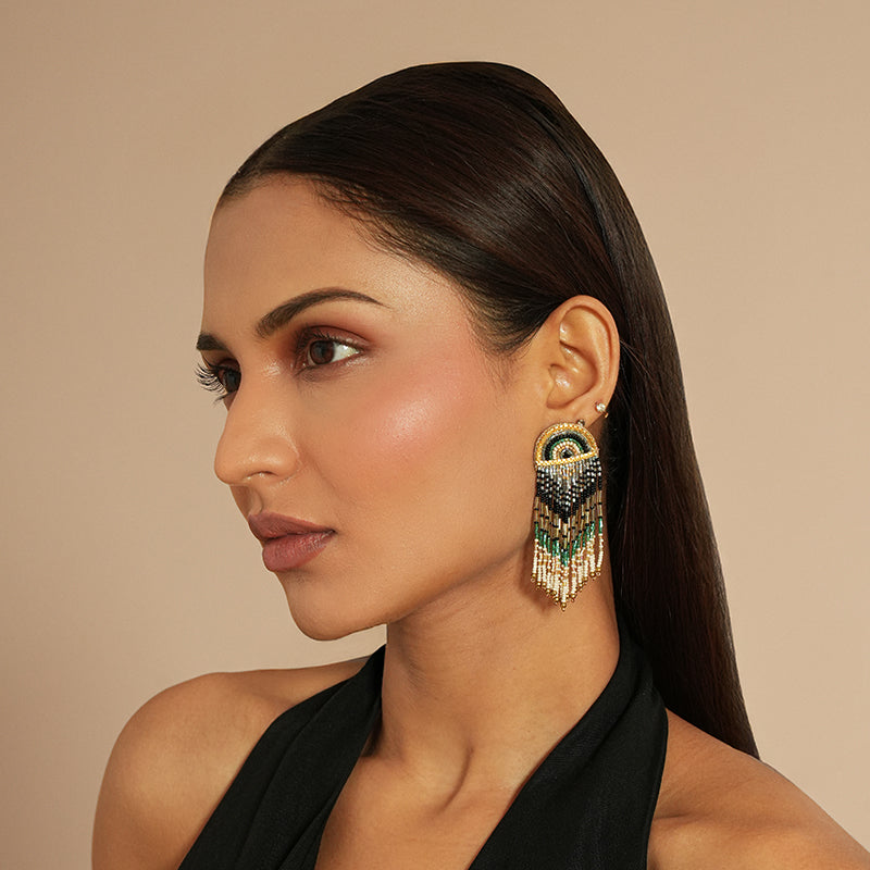 Woman wearing a pair of ornate earrings against a beige background